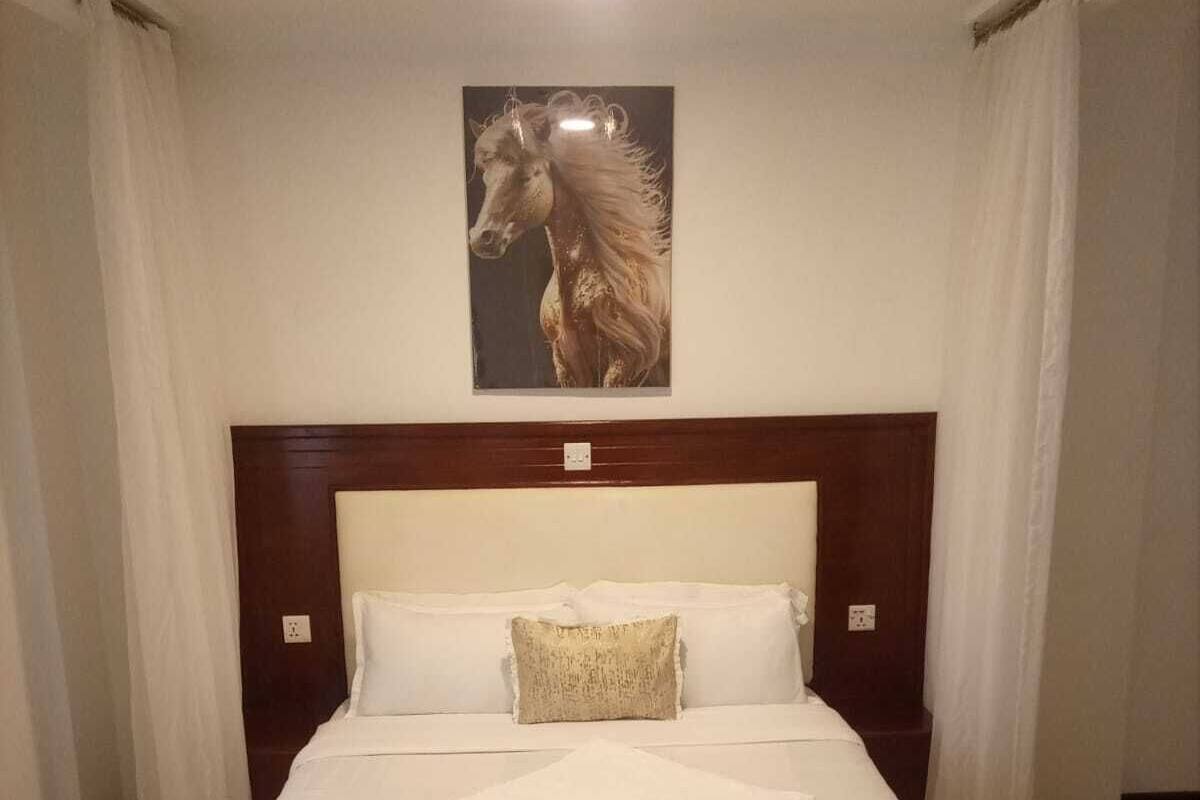 A neatly made bed with a wooden headboard, white bedding, and a decorative pillow.