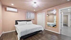 Een slaapkamer met een bed, een grote spiegel, een kroonluchter en een deur.