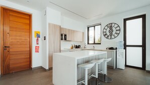 A modern kitchen with a central island, bar stools, a clock, and a water dispenser. - Villa Ektoras at Periyiali Resort with  modern design, and amenities.  (Paralimni)