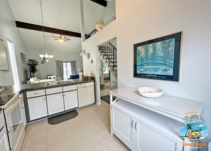 Une cuisine moderne avec des meubles blancs, un plan de travail en granit et un ventilateur de plafond.
