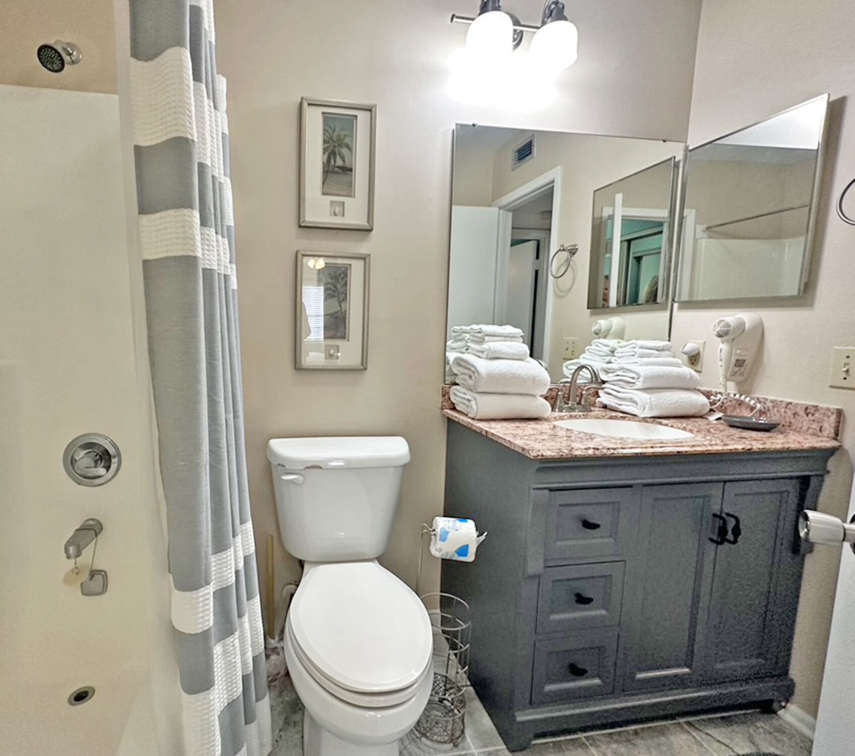 Een badkamer met toilet, wastafel met spiegel en douchegordijn.
