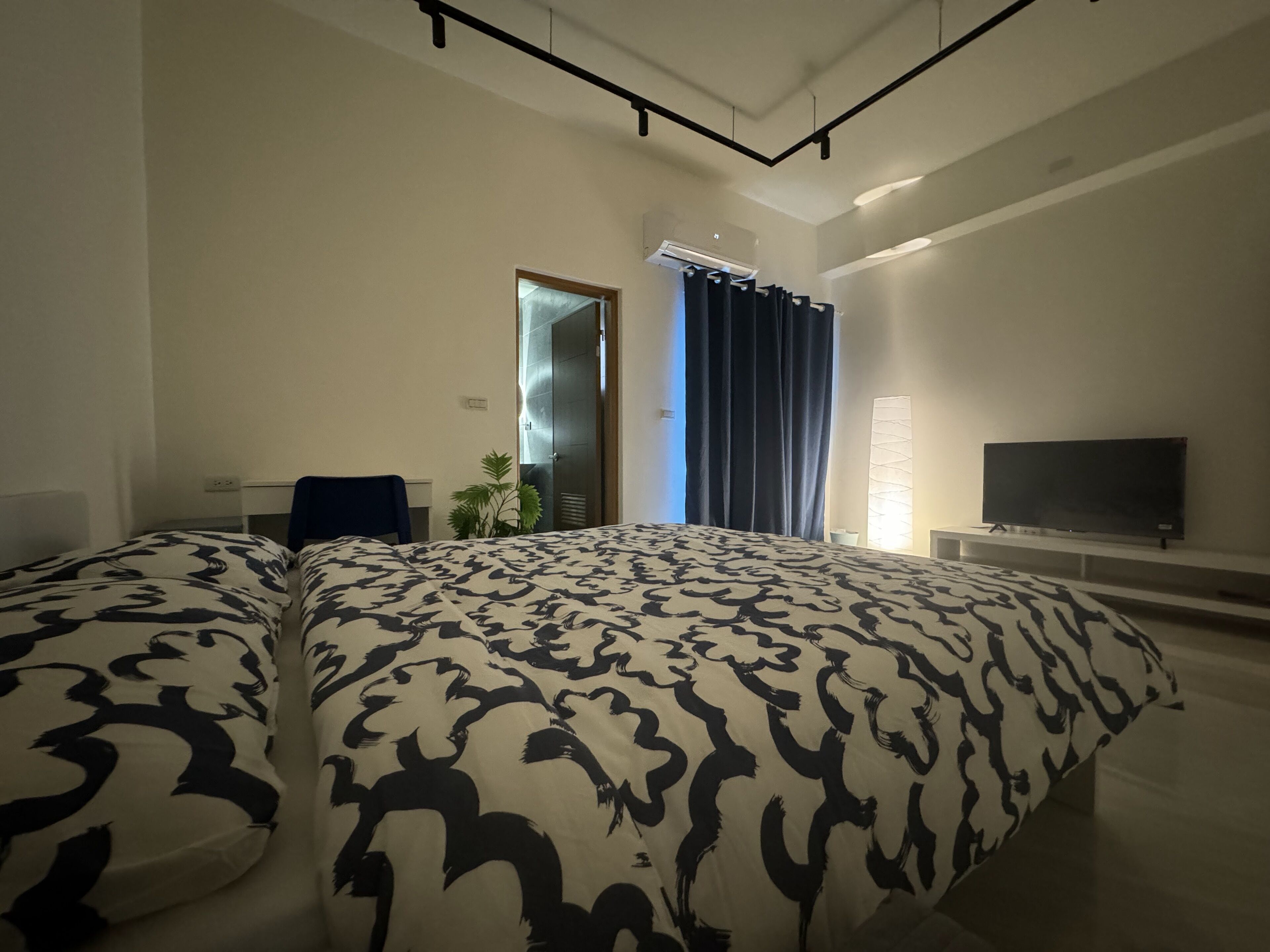 Ein modernes Hotelzimmer mit einem großen Bett, einem Fernseher und einem Schreibtisch.