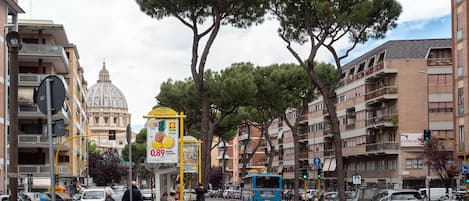 A street scene with a bus, parked cars, and a bus stop.