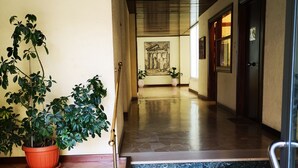 Un corridoio d'albergo con una scala in marmo, piante in vaso e un quadro appeso al muro.