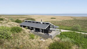 A modern beach house with a flat roof, large windows, and a deck overlooking the ocean. - Nice home in Hvide Sande with sauna (Hvide Sande)