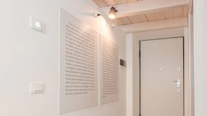 Ein Flur mit zwei großen Postern an der Wand, einer Tür und einer Leuchte über den Postern.