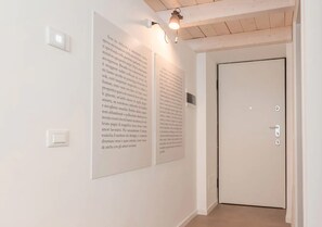 A hallway with two large posters on the wall, a door, and a light fixture above the posters.