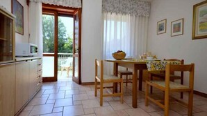 Un pequeño comedor con una mesa y sillas, un microondas y vistas al exterior.