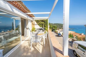 Ein Balkon mit Tisch und Stühlen, Blick auf das Meer und ein abgestellter Van.
