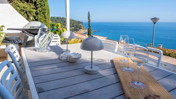 Ein Tisch mit Meerblick, Sitzgelegenheiten im Freien und ein Grill.