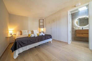Ein Schlafzimmer mit Bett, Nachttischlampen, einem Kleiderschrank und einem Badezimmer mit Spiegel.