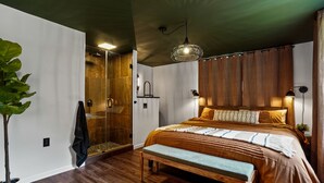 Ein modernes Schlafzimmer mit einem großen Bett, einer Bank, einer Dusche und einem Blumentopf.