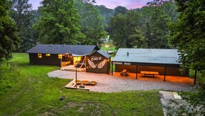 Ein rustikales Lodge mit einem großen Schild, das 'OHIO' und 'Hocking Hills' zeigt. Es bietet einen überdachten Sitzbereich im Freien und einen Picknicktisch.