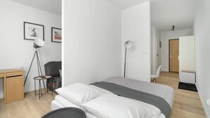 Un dormitorio moderno y minimalista con cama, mesita de noche y escritorio.