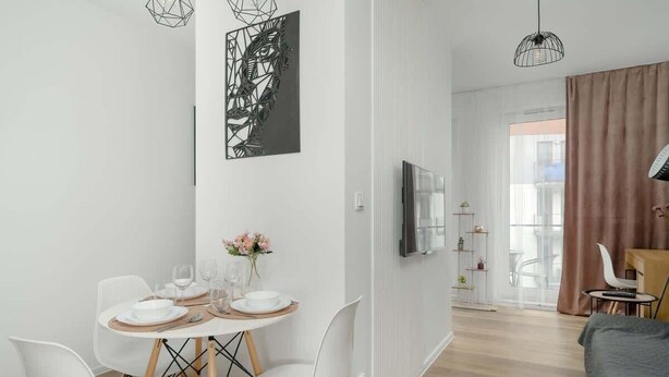 Un comedor moderno con una mesa redonda, sillas blancas y un cuadro abstracto en blanco y negro en la pared.