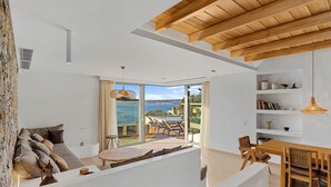 Sala de estar moderna com uma grande porta de vidro deslizante que dá para uma varanda com vista para o mar.