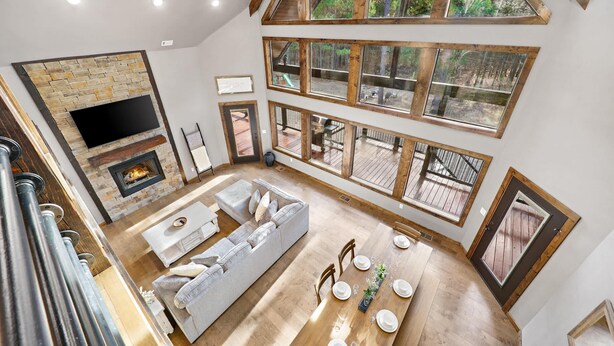 Un salón espacioso con chimenea, ventanas amplias y un techo alto.