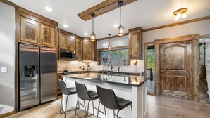 Una cocina moderna con armarios de madera, electrodomésticos de acero inoxidable y una isla central con taburetes de bar.