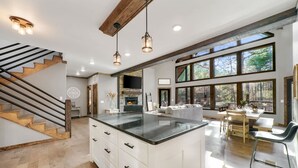 Una cocina amplia con una isla grande, un comedor con mesa y sillas, y una escalera con escalones de madera.