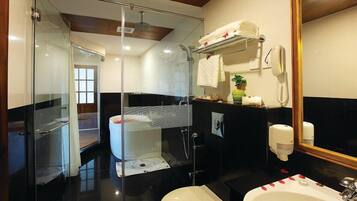 Un baño moderno con cabina de ducha de vidrio, inodoro blanco, lavabo con espejo y toallero con toallas.