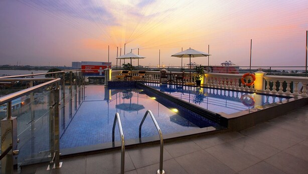 A swimming pool with a glass railing, umbrellas, and a lifebuoy. - LE MARITIME KOCHI (Kochi)