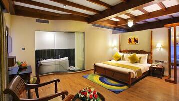 Quarto de hotel espaçoso com uma cama grande, área de estar com uma poltrona e uma mesa, escrivaninha e banheiro com banheira.