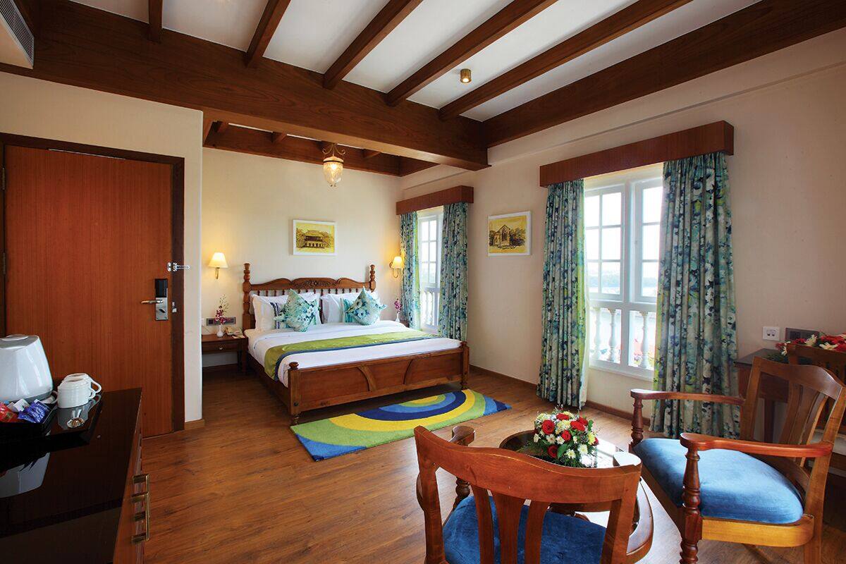 A hotel room with a wooden bed, a desk with a coffee maker, and a chair.