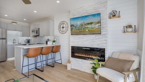 A modern kitchen with a central island, a fireplace, and a dining area with bar stools. - Amazing 1-bd Beach Villa, best location Hilton Head Island -Heart of the Island! (Hilton Head Island)