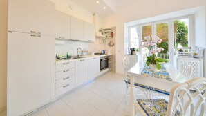 Una cucina moderna con mobili bianchi, forno integrato e zona pranzo con tavolo e sedie.