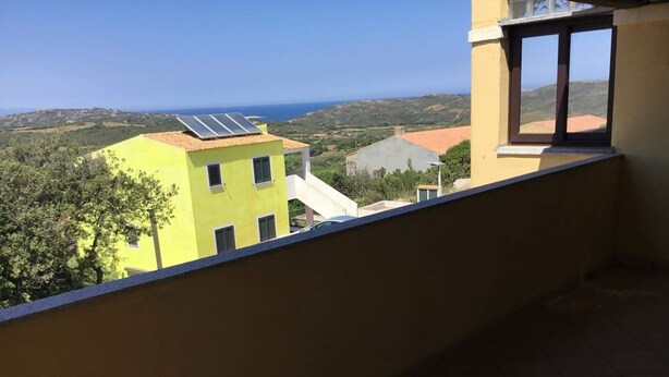 Uma varanda com vista para um edifício amarelo e o mar.