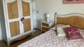 Quarto com cama, mesa de cabeceira, luminária e guarda-roupa.