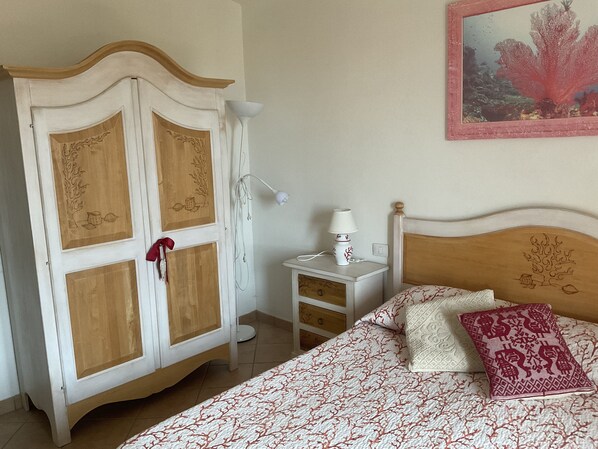 Un dormitorio con cama, mesita de noche, lámpara y armario.