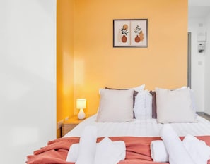 Une chambre dâhĂŽtel avec un lit, des oreillers, une couverture, une lampe de chevet et un tableau encadrĂ© au mur.