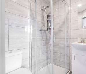 Une salle de bain moderne avec une douche à parois de verre, un lavabo blanc et des toilettes.