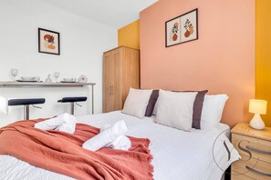 A hotel room with a bed, a desk with a chair, a wardrobe, and a nightstand with a lamp. - Studio 1E – Cozy Stay with Wi-Fi + TV (Stoke-on-Trent)