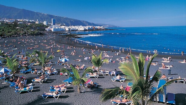 A crowded beach with numerous sun loungers and umbrellas, a clear blue sky, and a mountainous backdrop. - Apartamento Amplio y Tranquilo con Vistas al Mar 4 (CN)