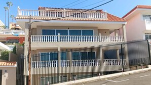A two-story building with a balcony, a gated entrance, and a clear sky. - Apartamento Amplio y Tranquilo con Vistas al Mar 4 (CN)