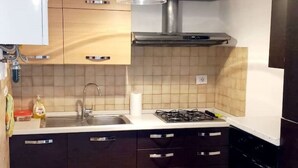 A kitchen with dark cabinets, a stainless steel sink, and a gas stove. - 2 Bedroom Apartment in Pisa (Pisa)