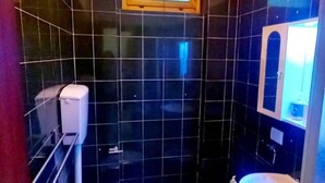 A bathroom with black tiles, a white toilet, a white sink, and a mirror. - 2 Bedroom Apartment in Pisa (Pisa)