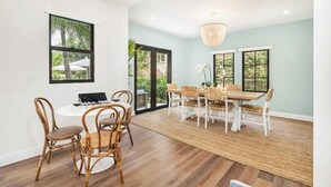 A dining area with two round tables, wicker chairs, and a chandelier.