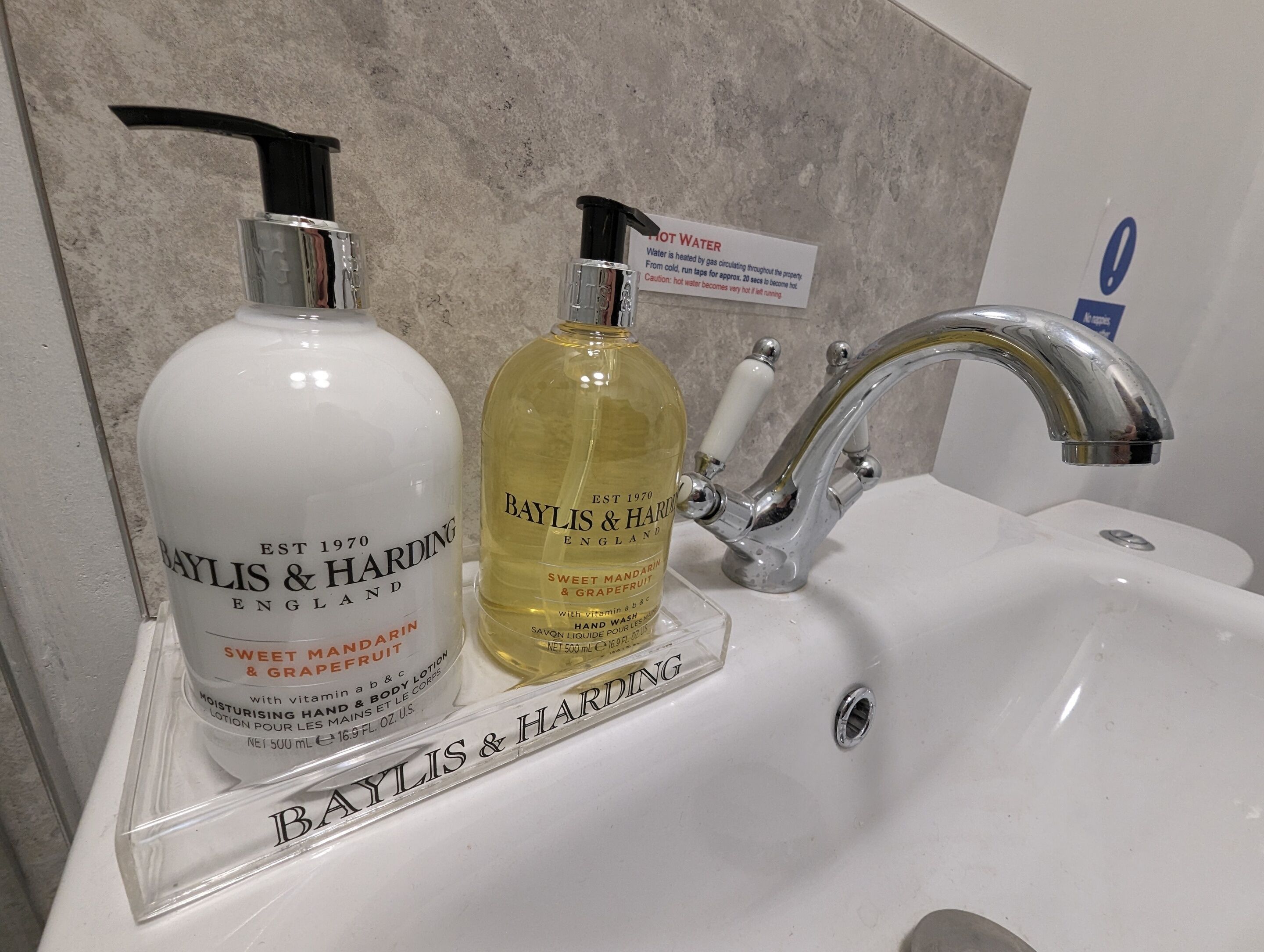 Kaksi Baylis & Harding -tuotepulloa kylpyhuoneen pesualtaalla, jonka yläpuolella on hana.