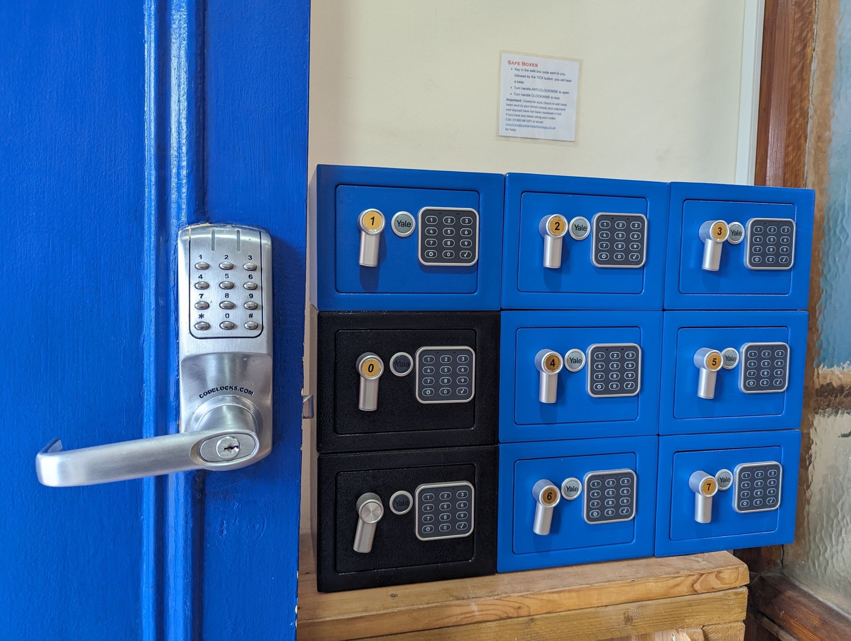 A blue door with a numeric keypad lock and a safe with multiple Yale locks.