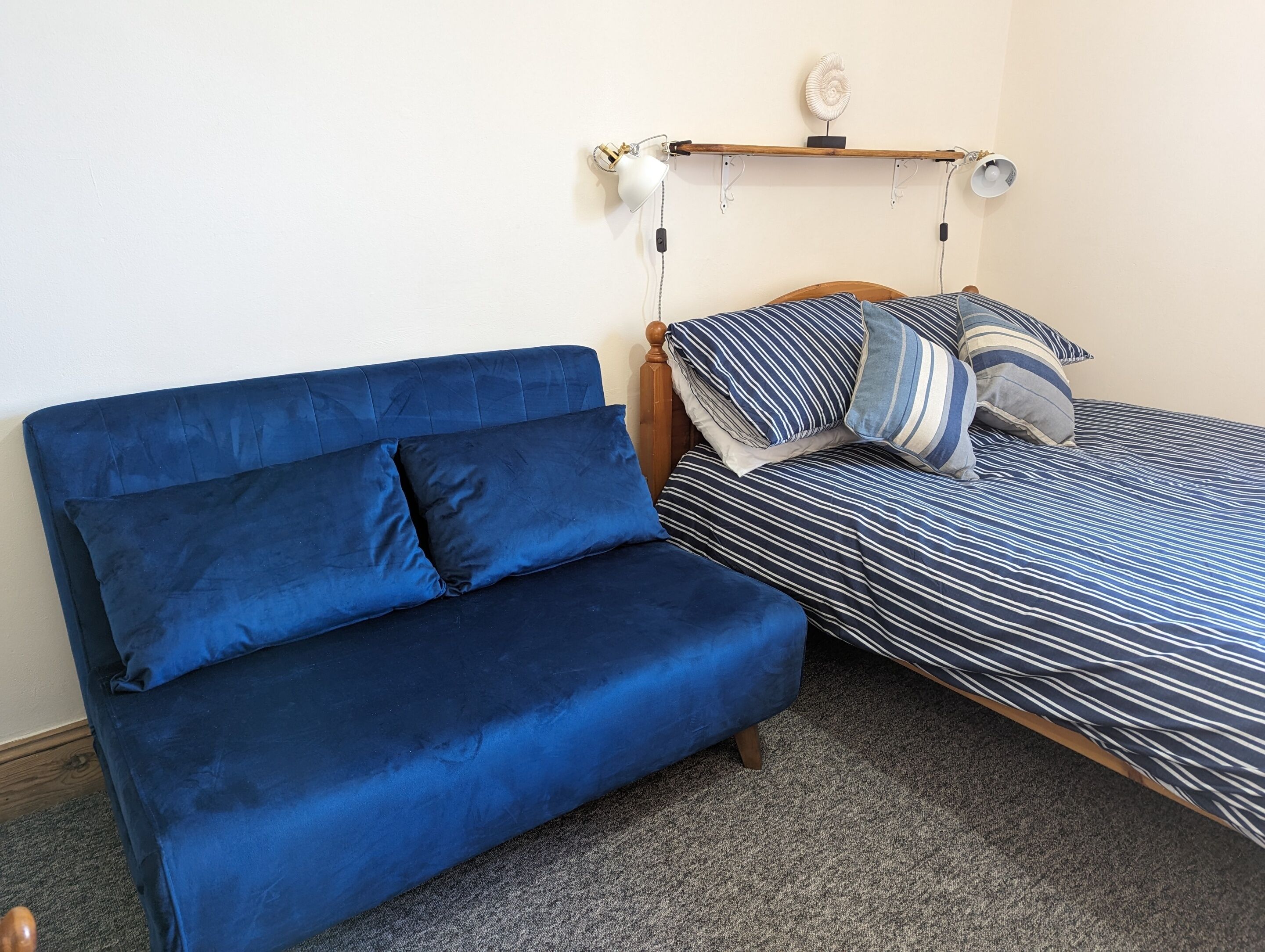 Una habitación con un sofá azul y una cama con ropa de cama a rayas.