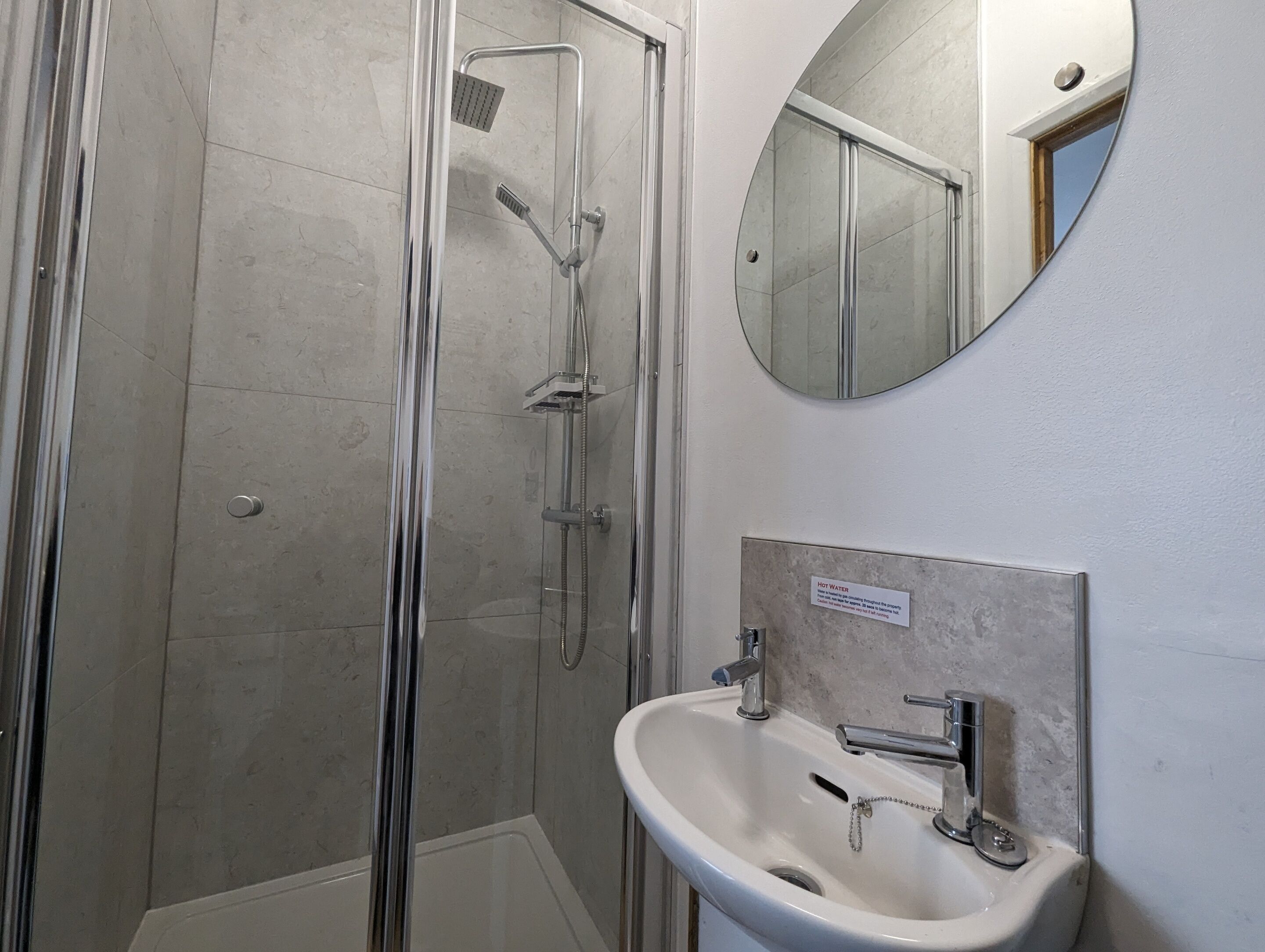 A modern bathroom with a glass-enclosed shower, a white sink, and a mirror on the wall.