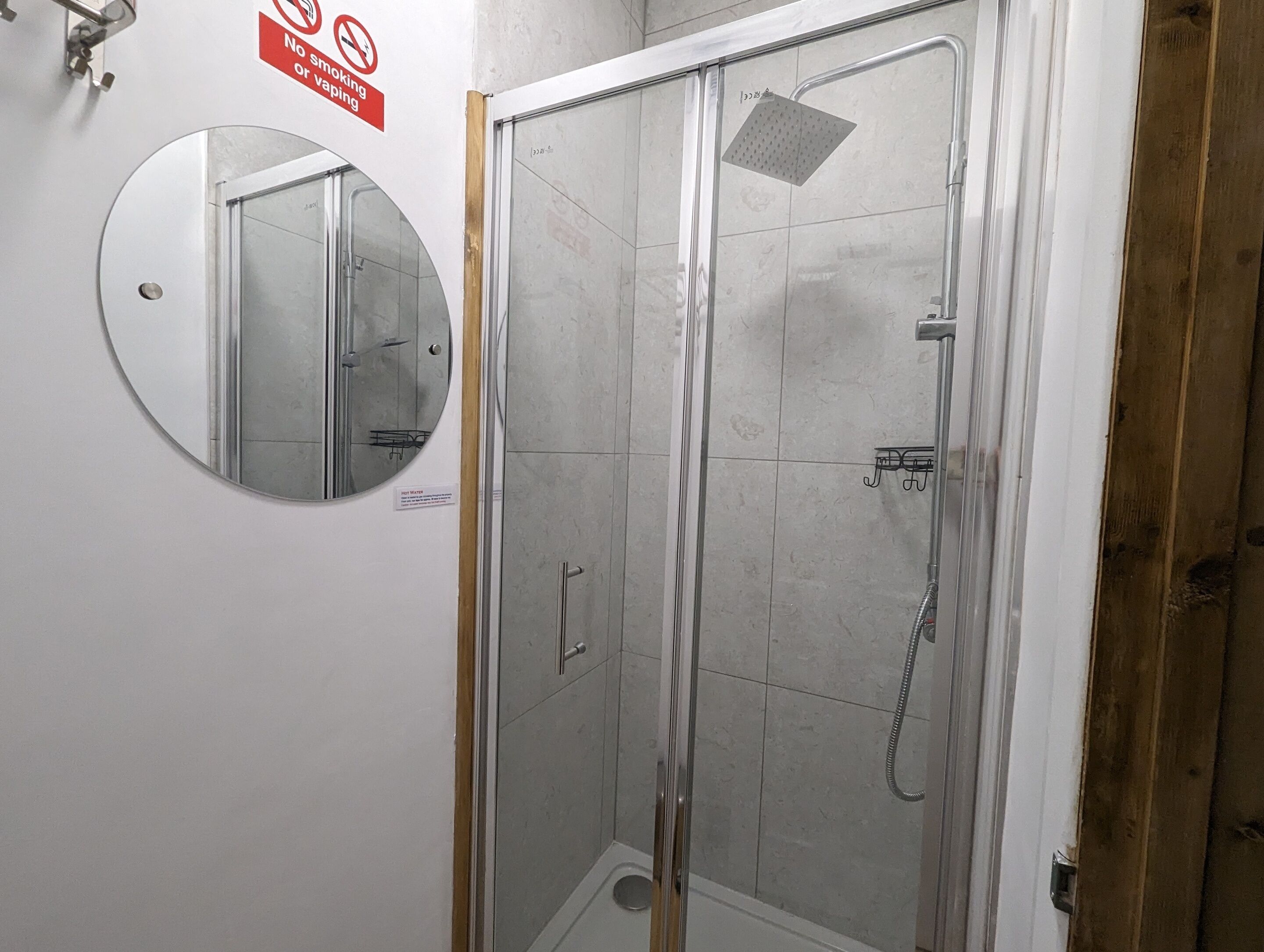 Um chuveiro com divisória de vidro, com um chuveiro manual e um chuveiro quadrado fixado na parede.