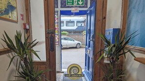 A hotel entrance with a fire exit sign, a door with a "Shut" sign, and a "Jurassic World" sign on the door. - Jurassic Bay Holidays (Weymouth)