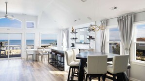 Una cocina amplia con una isla grande, armarios blancos y vistas al océano.