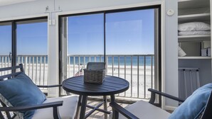Een balkon met een tafel en stoelen, met uitzicht op een strand.