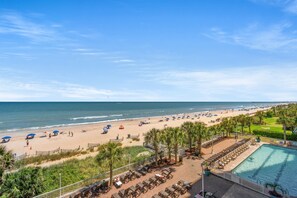 Un resort en la playa con piscina, sillones de descanso y sombrillas.