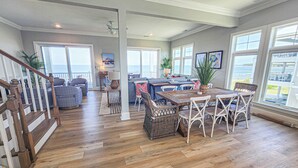 A spacious living area with a wooden floor, a dining table with chairs, a sofa, and a staircase. - Gorgeous New 5 BDR, 4 BA Beach Home With Tower Outlook Suite! (Cape Charles)